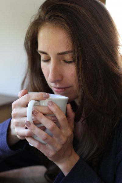 Woman with closed eyes holding a mug 