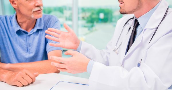 A man with a white mustache discusses his health with a doctor.